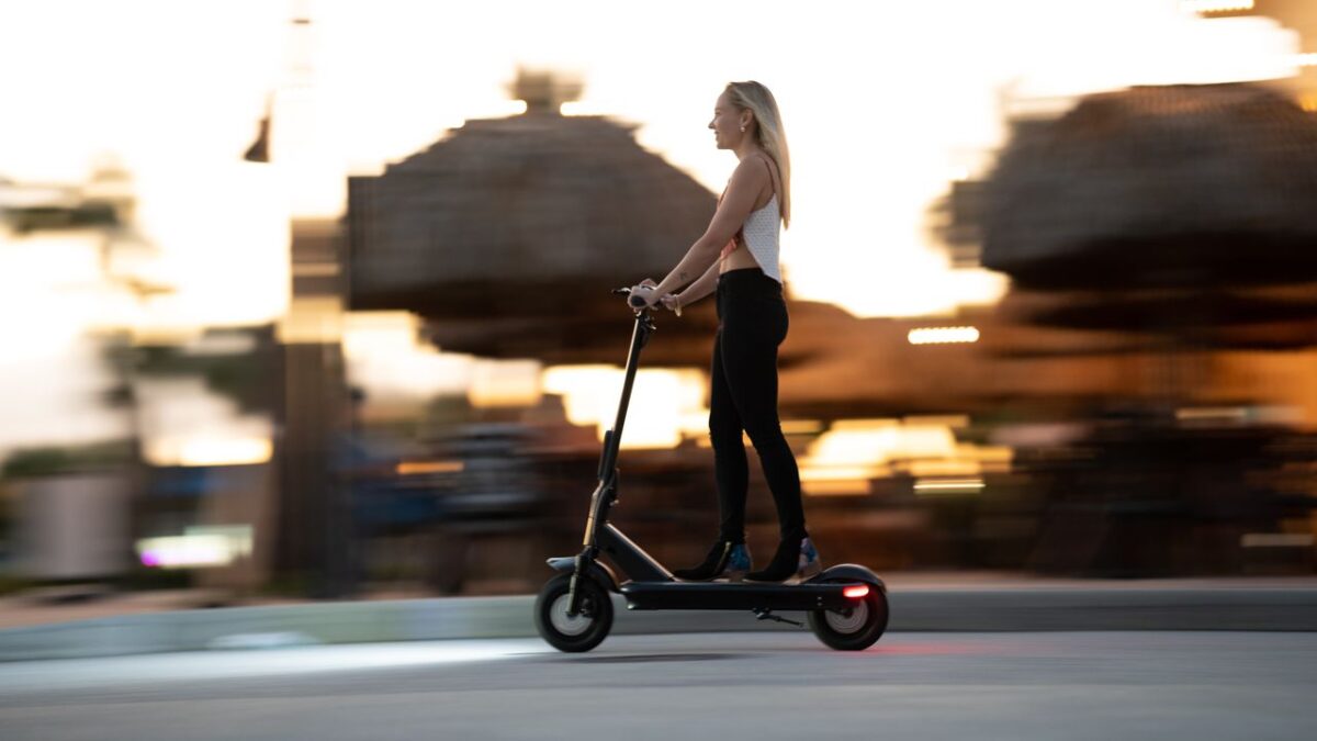 Services Woman enjoying an evening ride on an electric scooter with motion blur capturing speed and excitement.