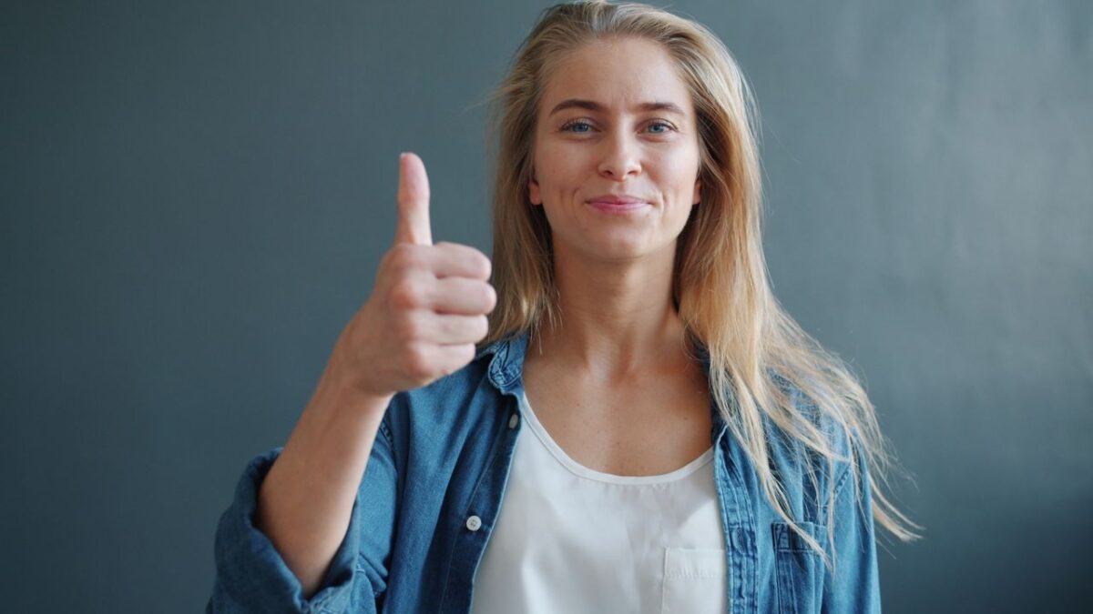 Services Portrait of a smiling woman giving a thumbs up against a neutral background.
