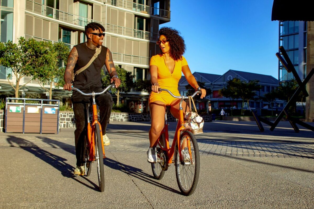Services A joyful couple biking through urban Cape Town under a sunny sky.